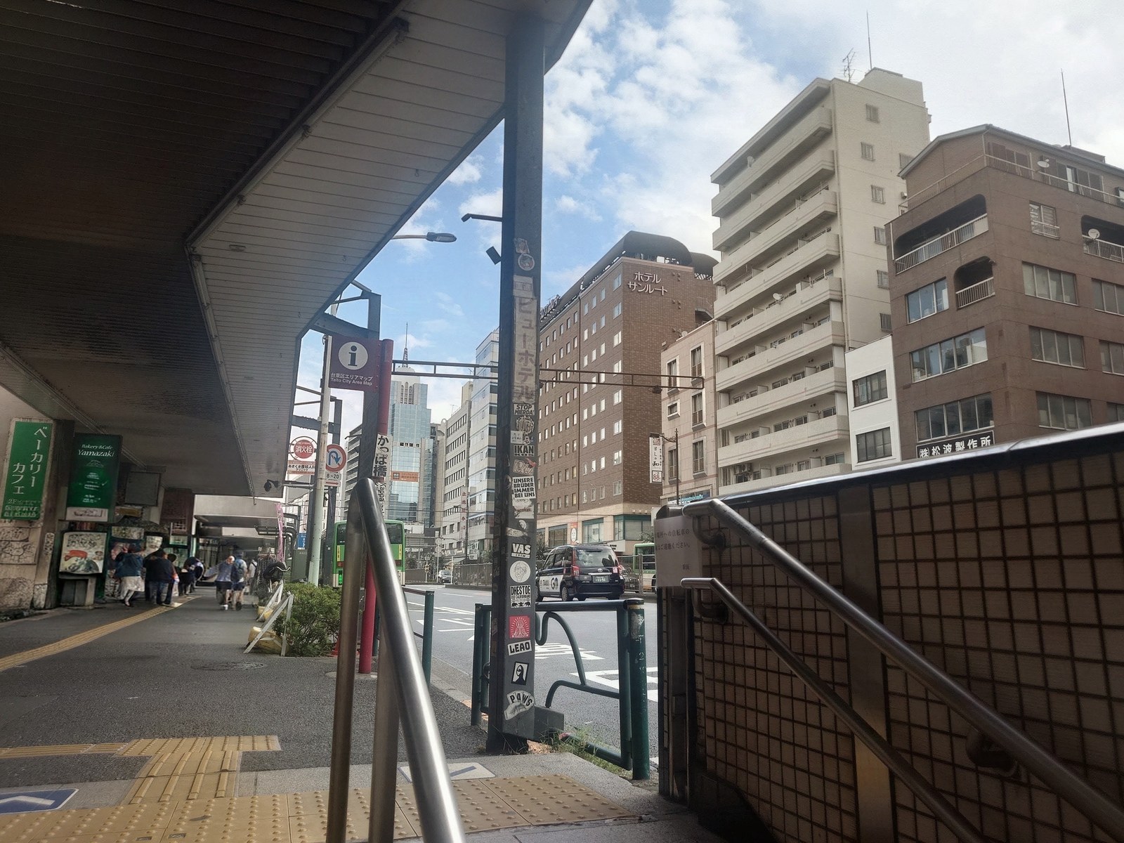 3番出口を上がったところ。右手に横断歩道があり、通りの先にホテルの建物が見えています。