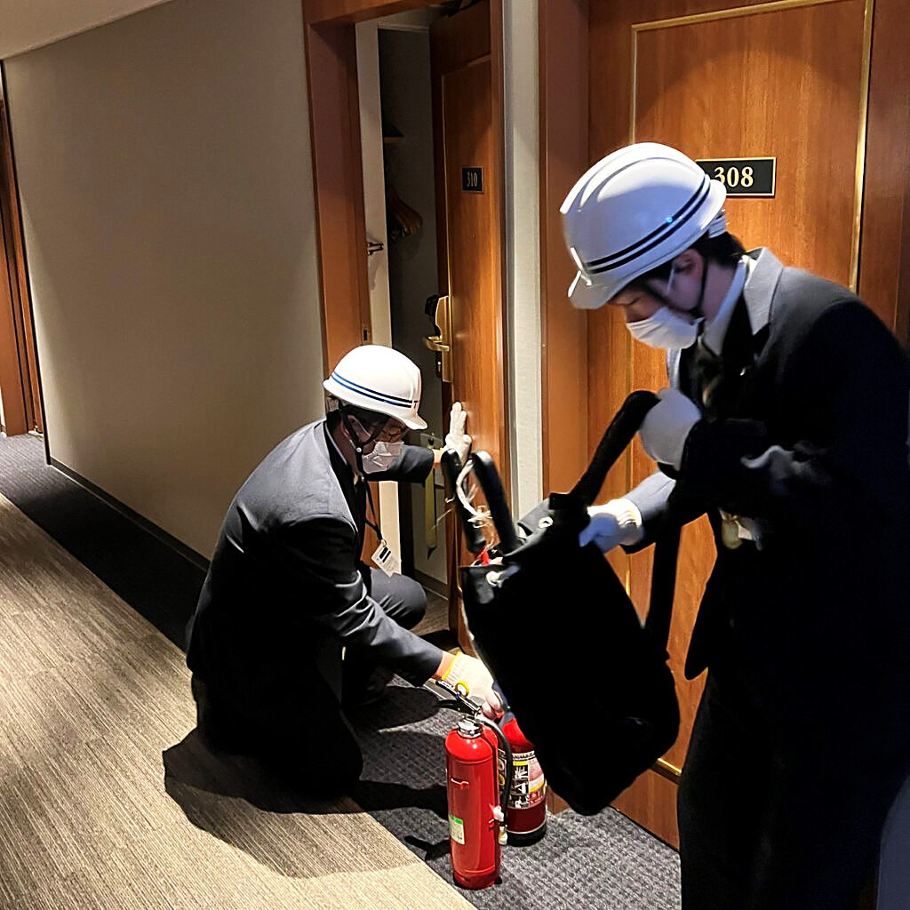 客室階の廊下で消火器の取り扱いを確認するホテルスタッフ